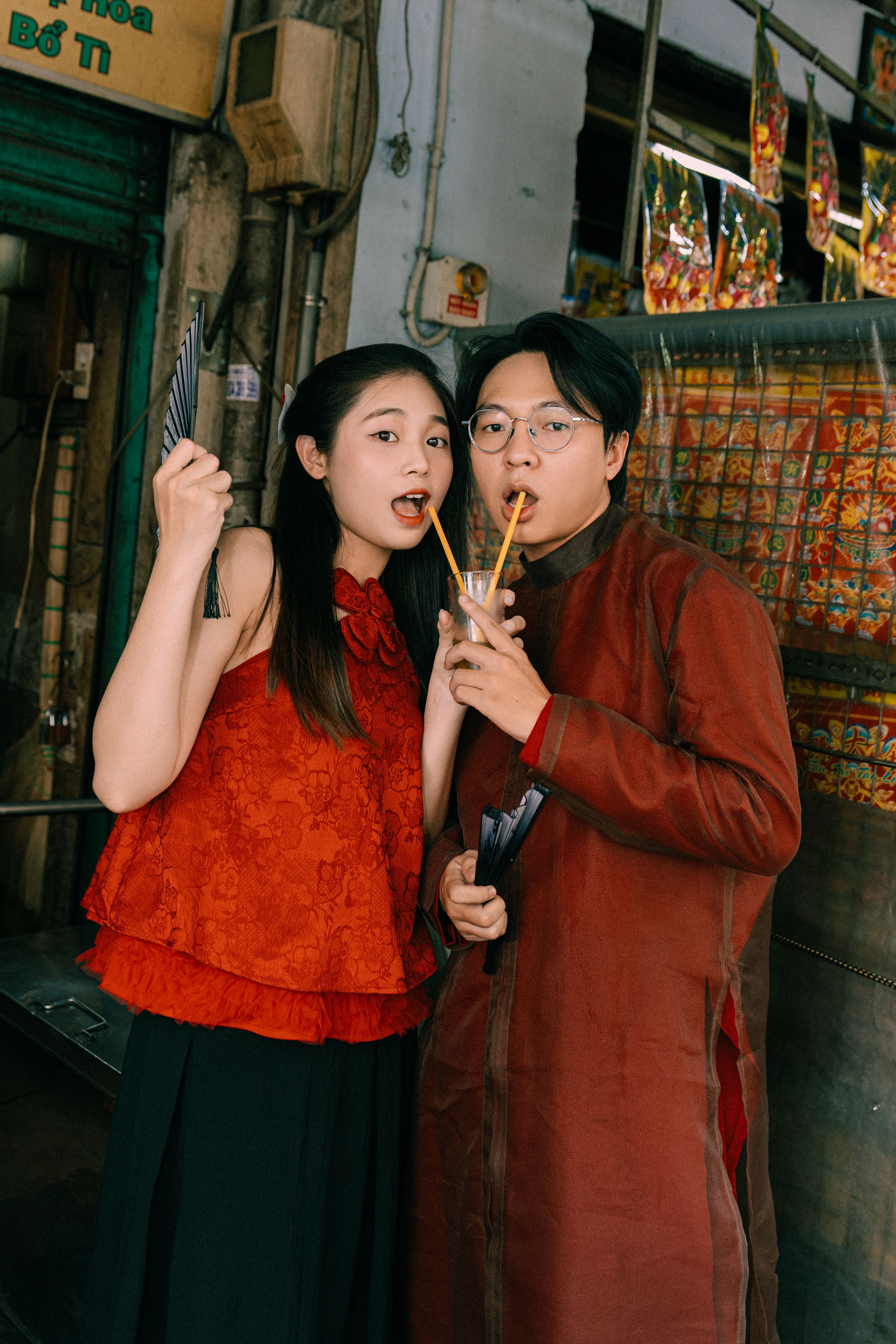 Candid shot of a young couple sipping drinks together in a colorful street setting.