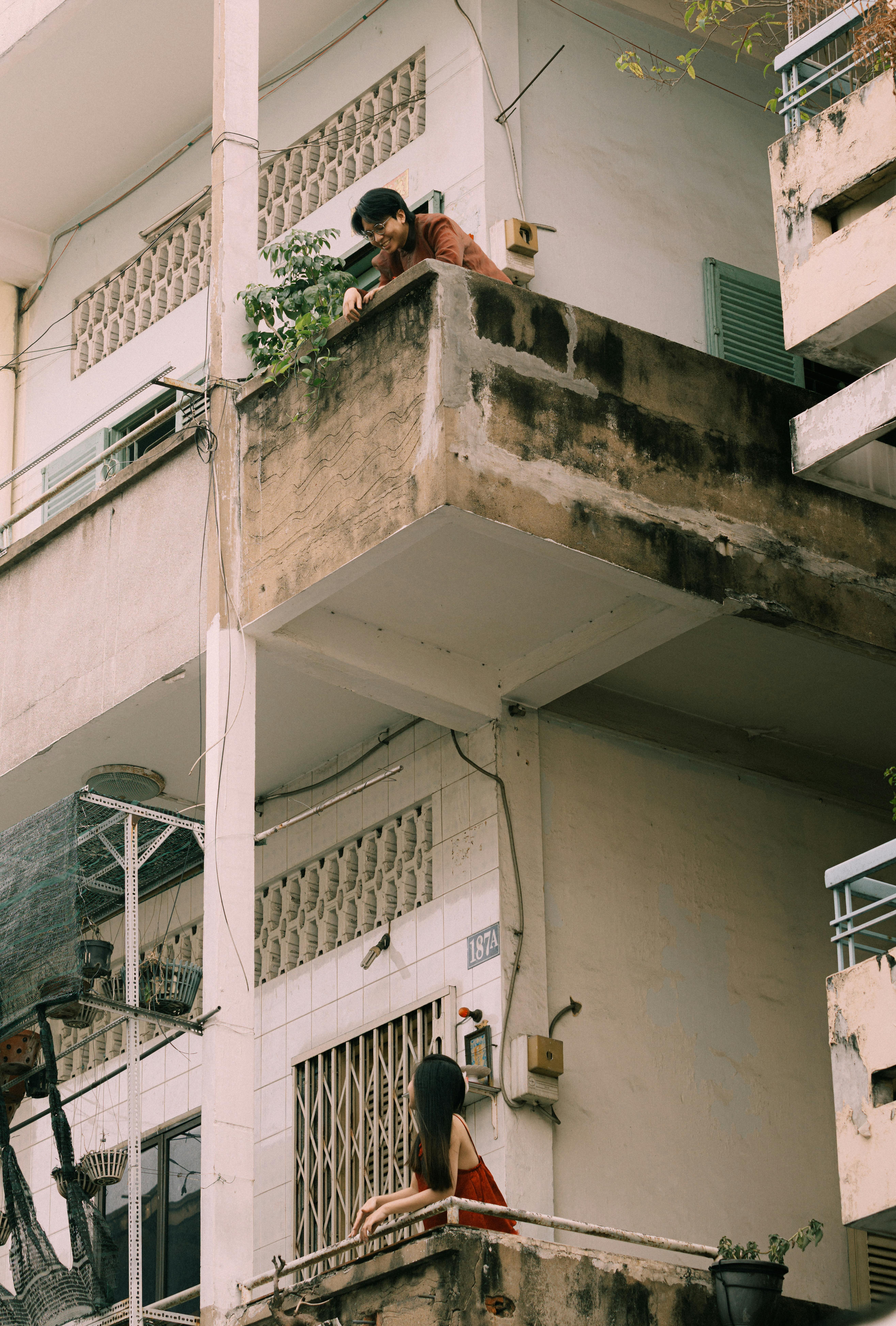 無料 コンクリートのバルコニー越しに2人の人物が会話する都会の風景。都市生活のダイナミクスを表現しています。 写真素材