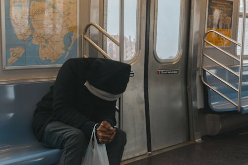 坐在火車長椅上的黑色連帽衫的人