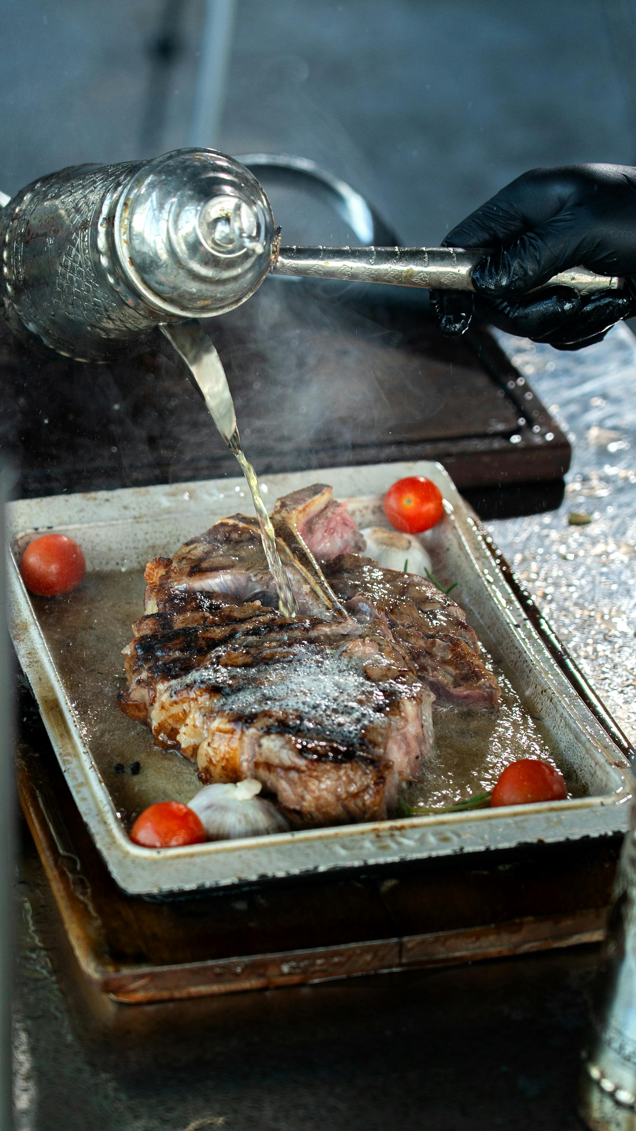 Gratis Steak panggang yang juicy dengan kaldu yang disiram di atasnya, dikelilingi oleh tomat ceri, menciptakan pemandangan kuliner yang mewah. Foto Stok