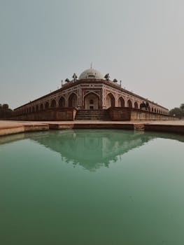 Historic Humayun's Tomb in Delhi reflected in a peaceful pool with clear skies.