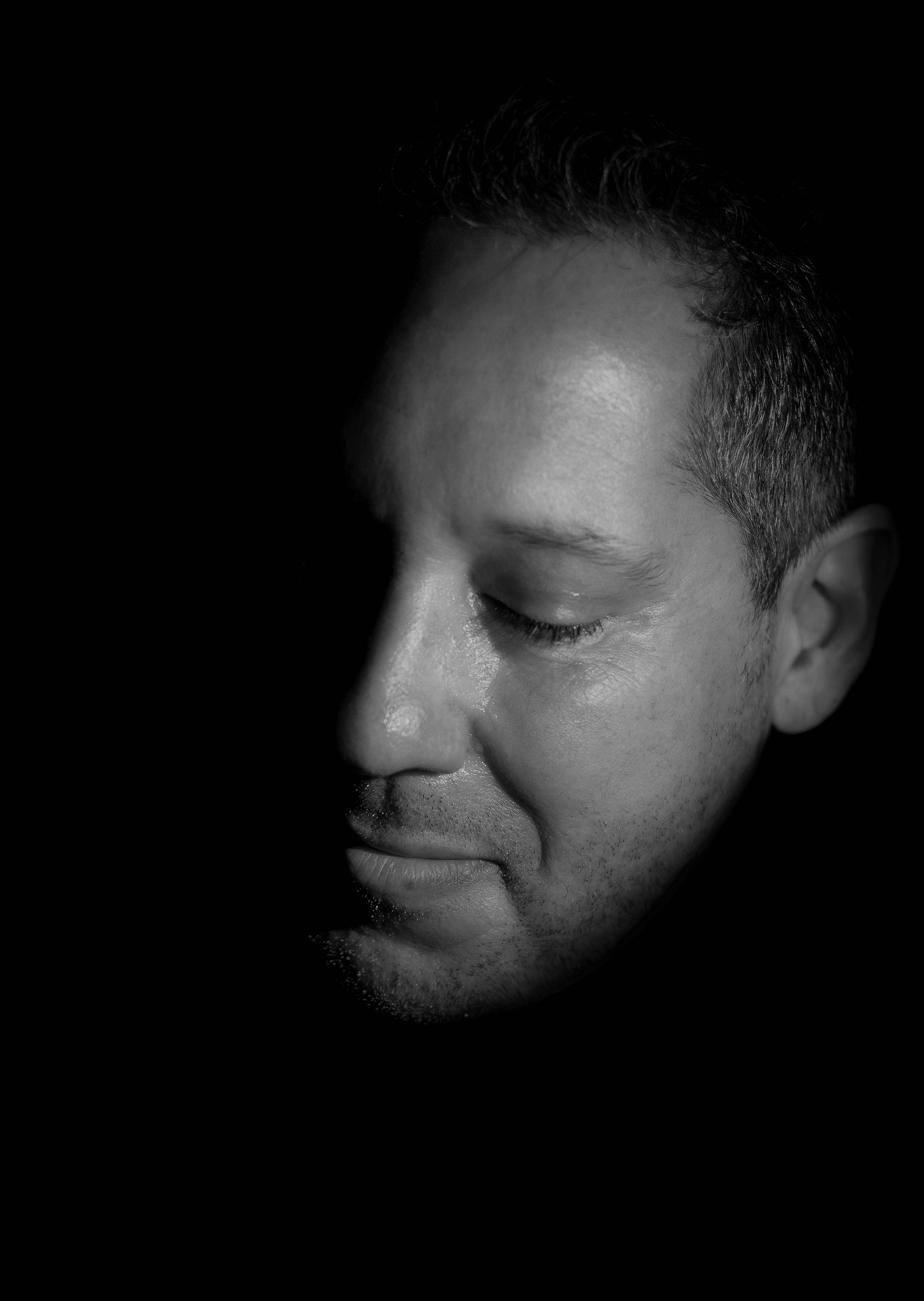 Gratis Potret hitam putih seorang pria yang penuh pertimbangan, dengan pencahayaan dan bayangan yang dramatis. Foto Stok