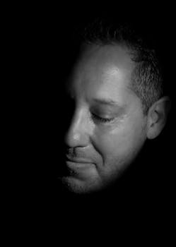 A thoughtful black and white portrait of a man with dramatic lighting and shadows.