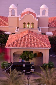 Aerial view of a Mediterranean-style villa with red tiled roof at dusk, featuring lush greenery.