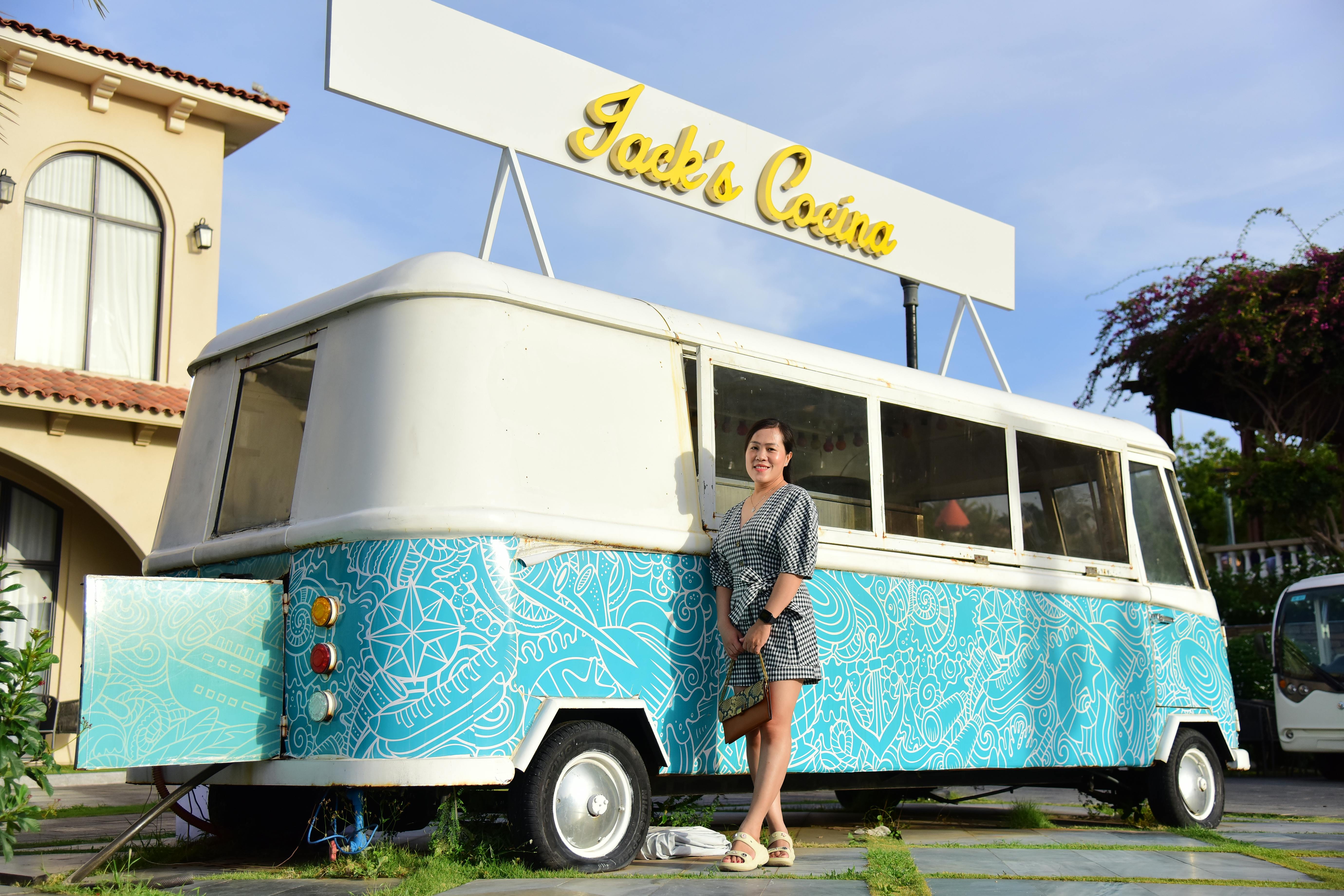 Gratis Seorang wanita berdiri di samping truk makanan artistik di Jack's Cocina pada hari yang cerah. Foto Stok