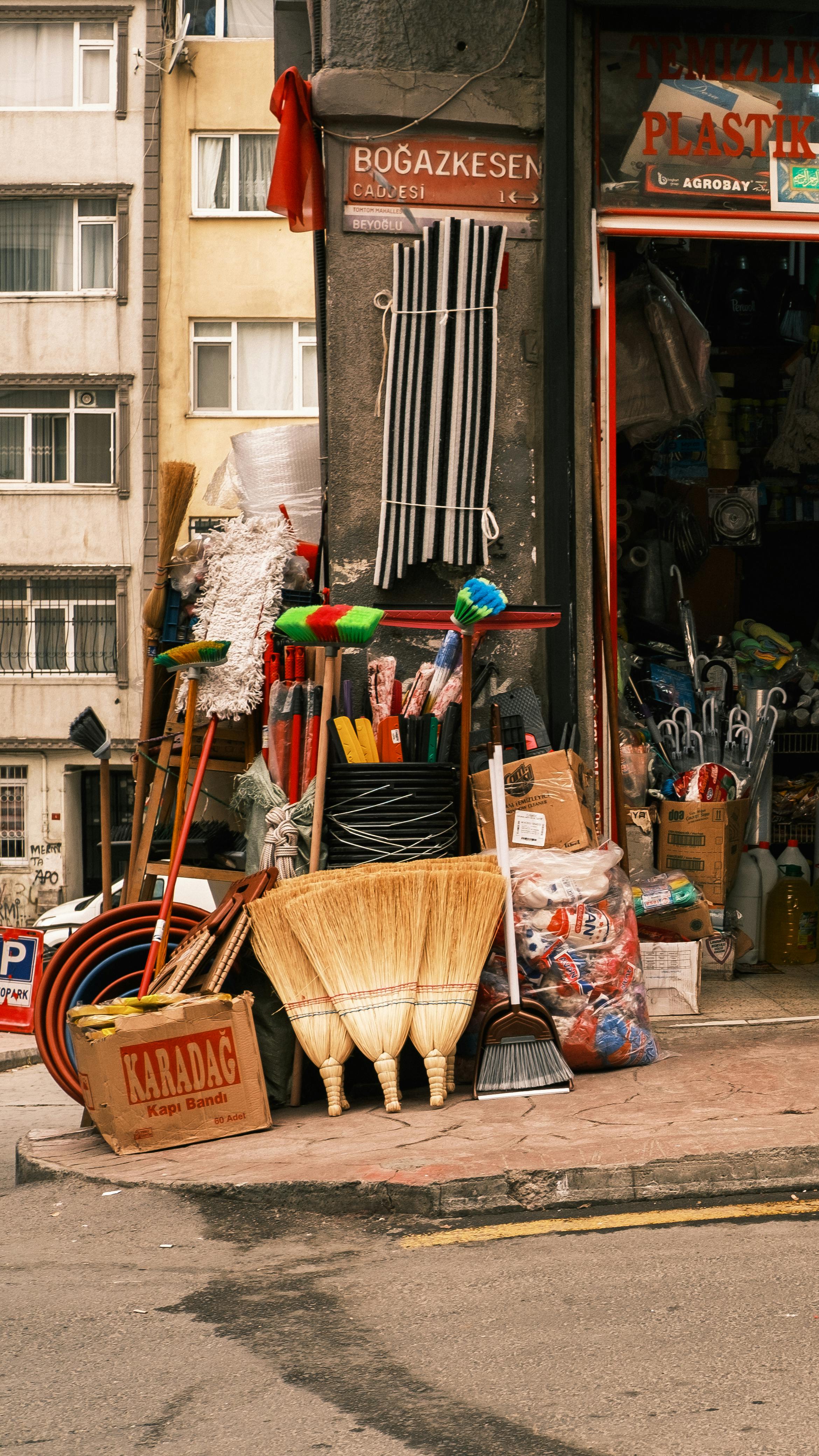 A colorful street display of cleaning supplies and household items outside a small hardware store in the city.