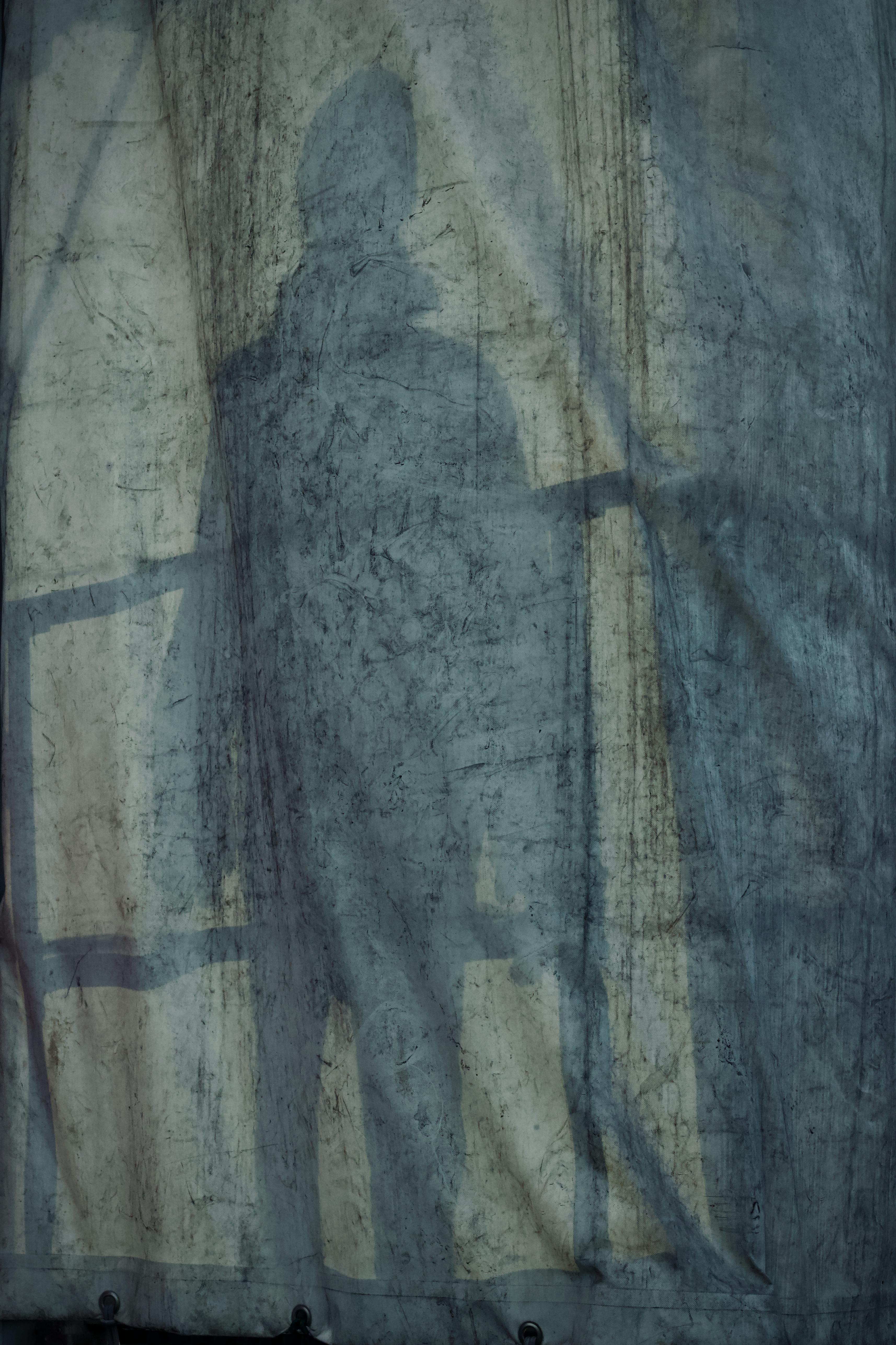 Free Shadow of a person seen through a textured, grungy curtain creating a mysterious effect. Stock Photo