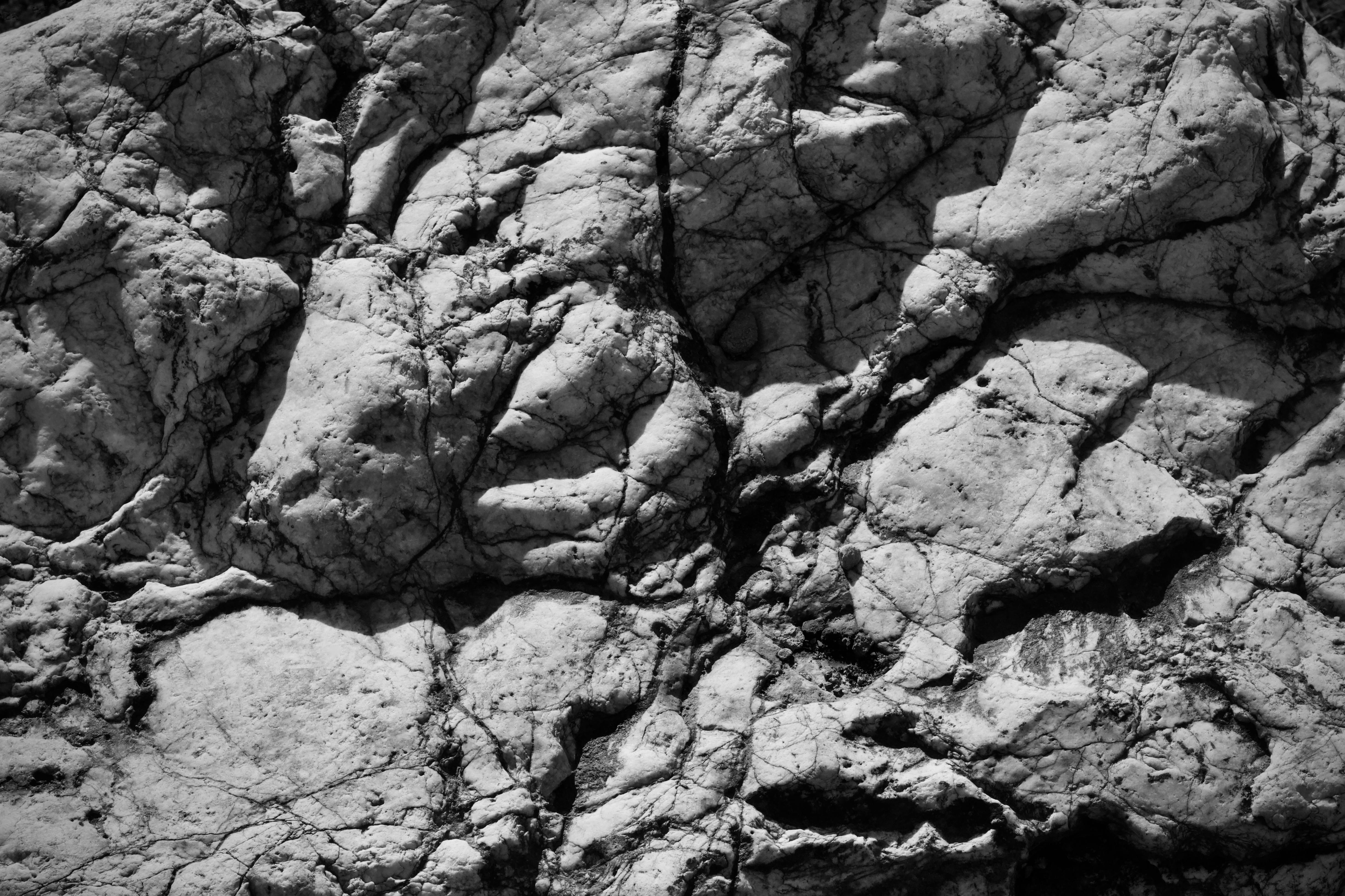 Gratis Detaljert svart-hvitt-bilde som viser teksturen til en robust steinoverflate med synlige sprekker. Arkivbilde