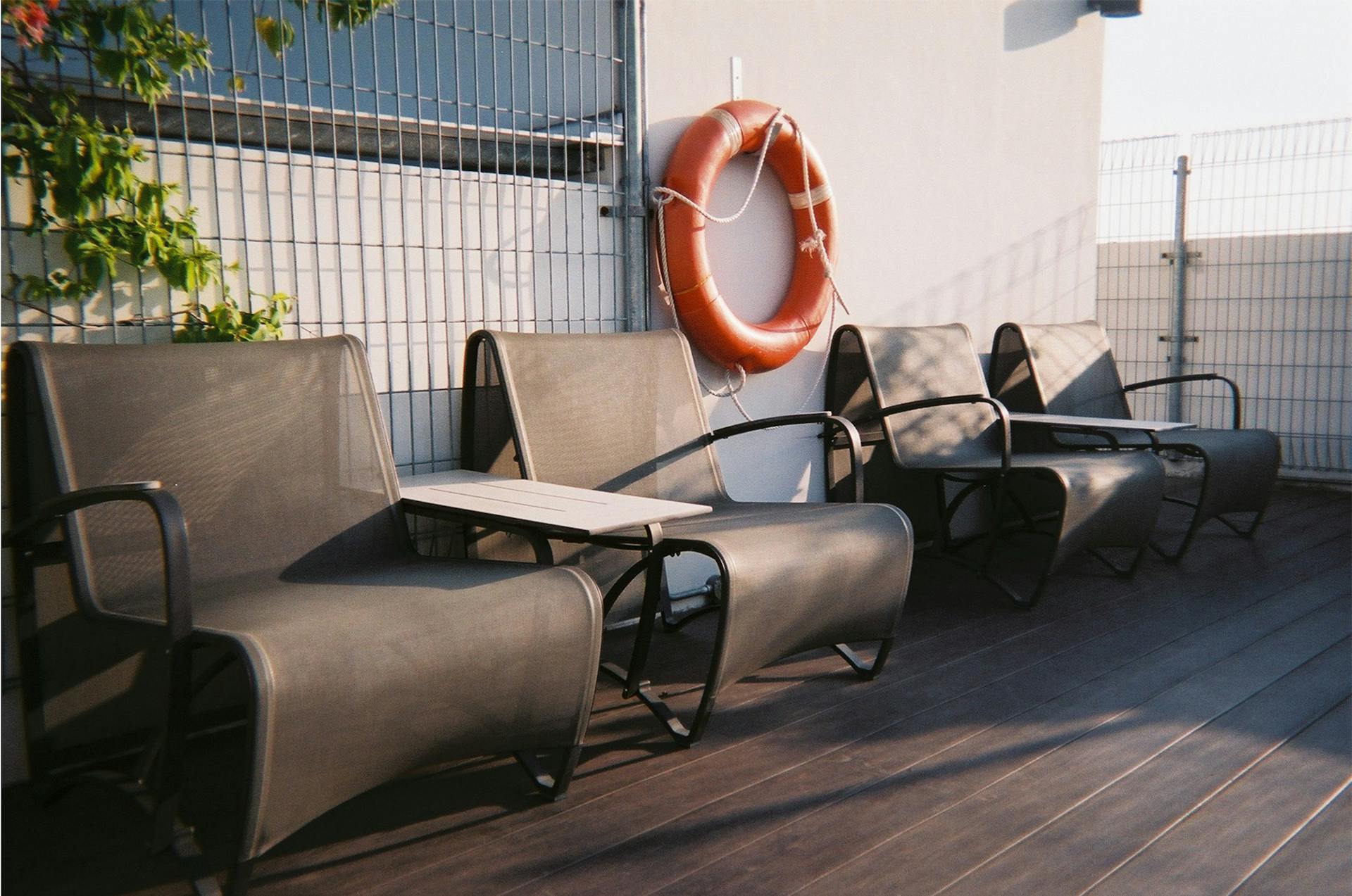 Contemporary lounge chairs on a sunny outdoor deck in Singapore with a lifebuoy and wooden floor.