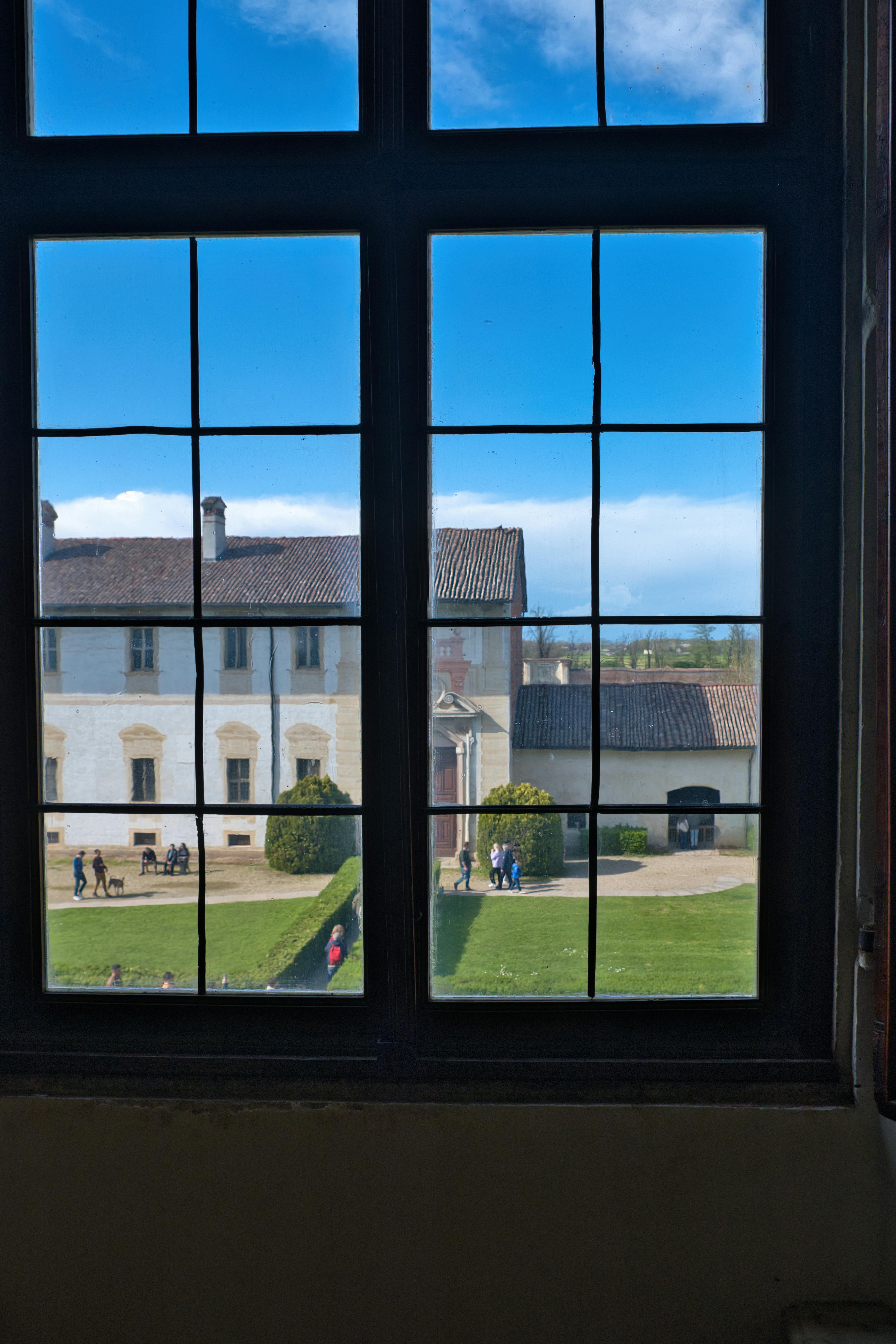 бесплатная Живописный вид на исторический внутренний двор в Павии, Италия, через большое окно. Стоковое фото