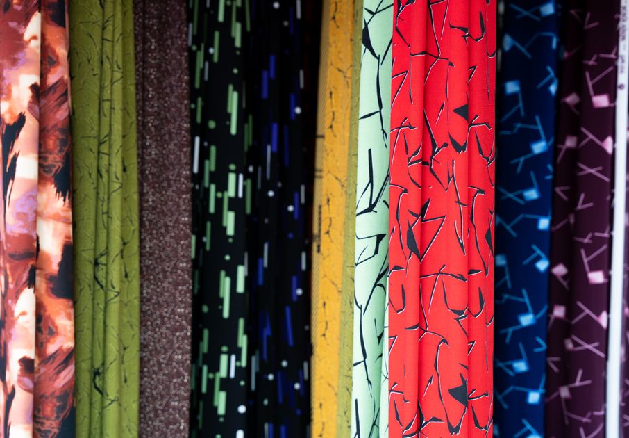 Bảng so sánh phương pháp in vải trên tường xưởng may với các mẫu vải polyester in hoa văn đặt cạnh nhau