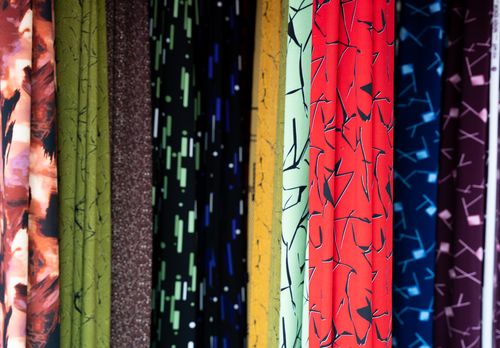 Free Vibrant rolls of patterned fabric on display at a market in Vietnam. Perfect for textile and design inspiration. Stock Photo