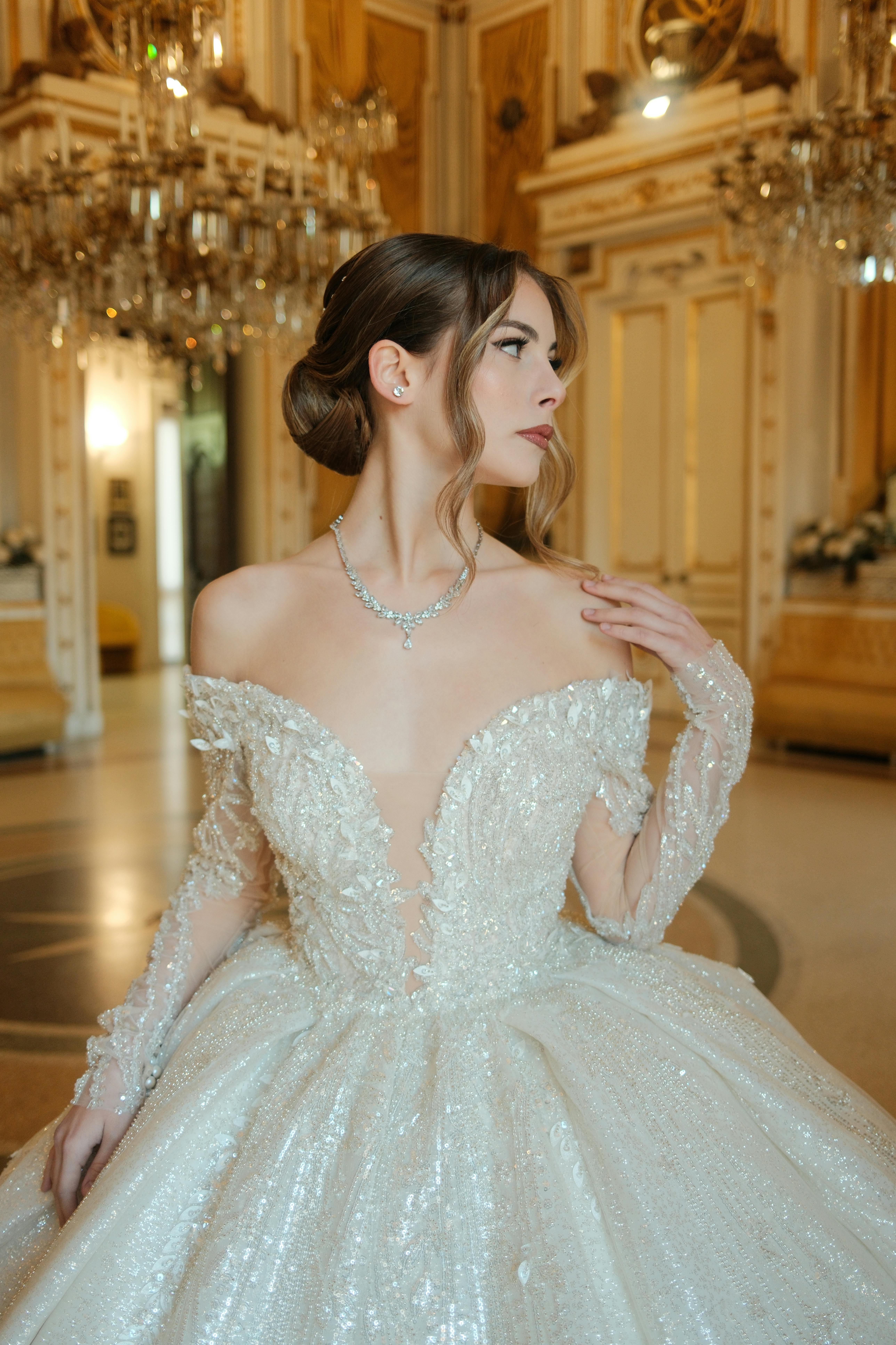 Gratis En fantastisk brud i en overdådig blondebrudekjole poserer grasiøst innendørs. Arkivbilde