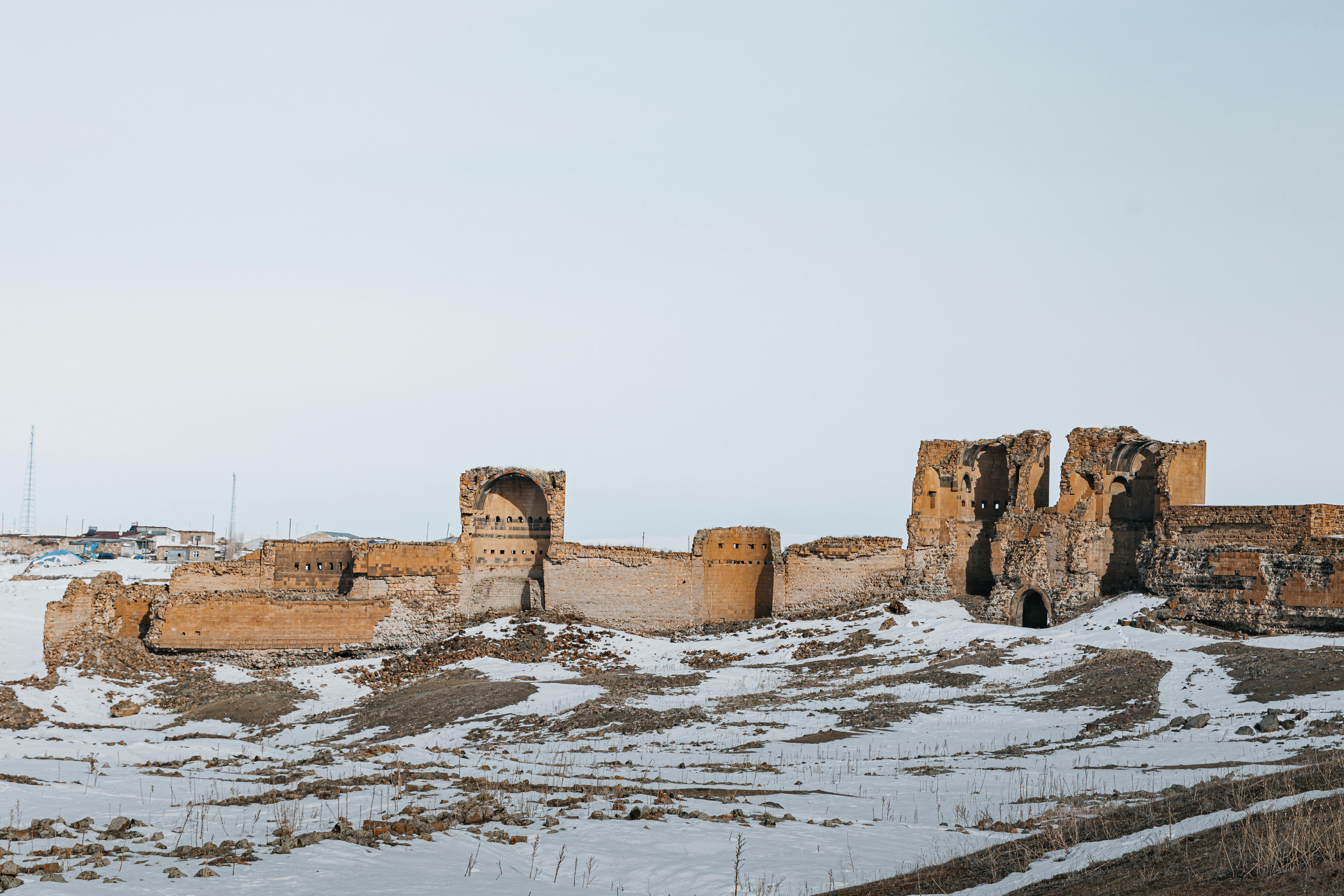 Scenic view of historical ruins covered in snow in Kars, Türkiye, conveying a wintery landscape.