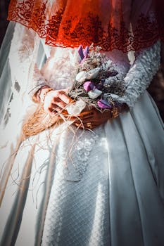 Beautiful bride in white dress holding a rustic bouquet, featuring delicate floral details and vibrant colors.