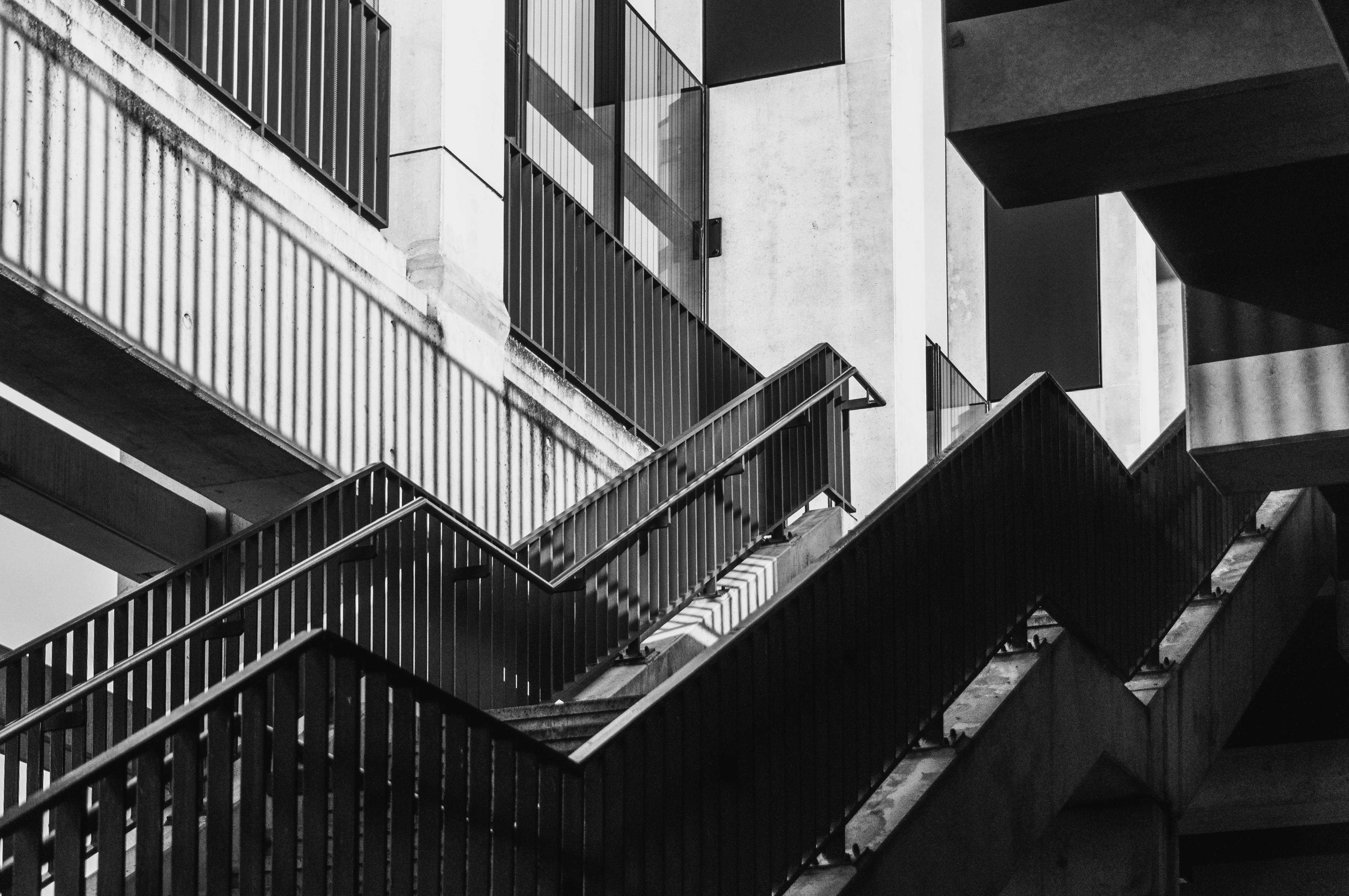 бесплатная Монохромное изображение геометрической бетонной лестницы с эффектными тенями. Стоковое фото