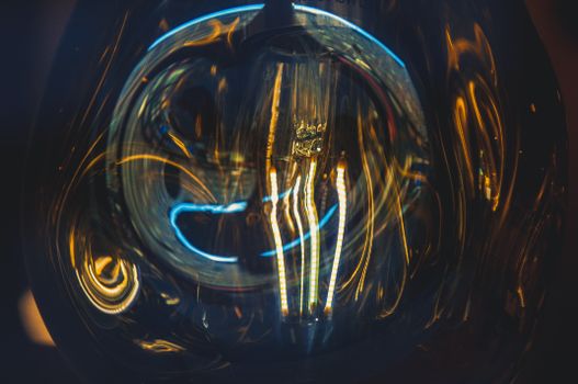 Dramatic close-up shot of a glowing light bulb filament with swirling colorful reflections.