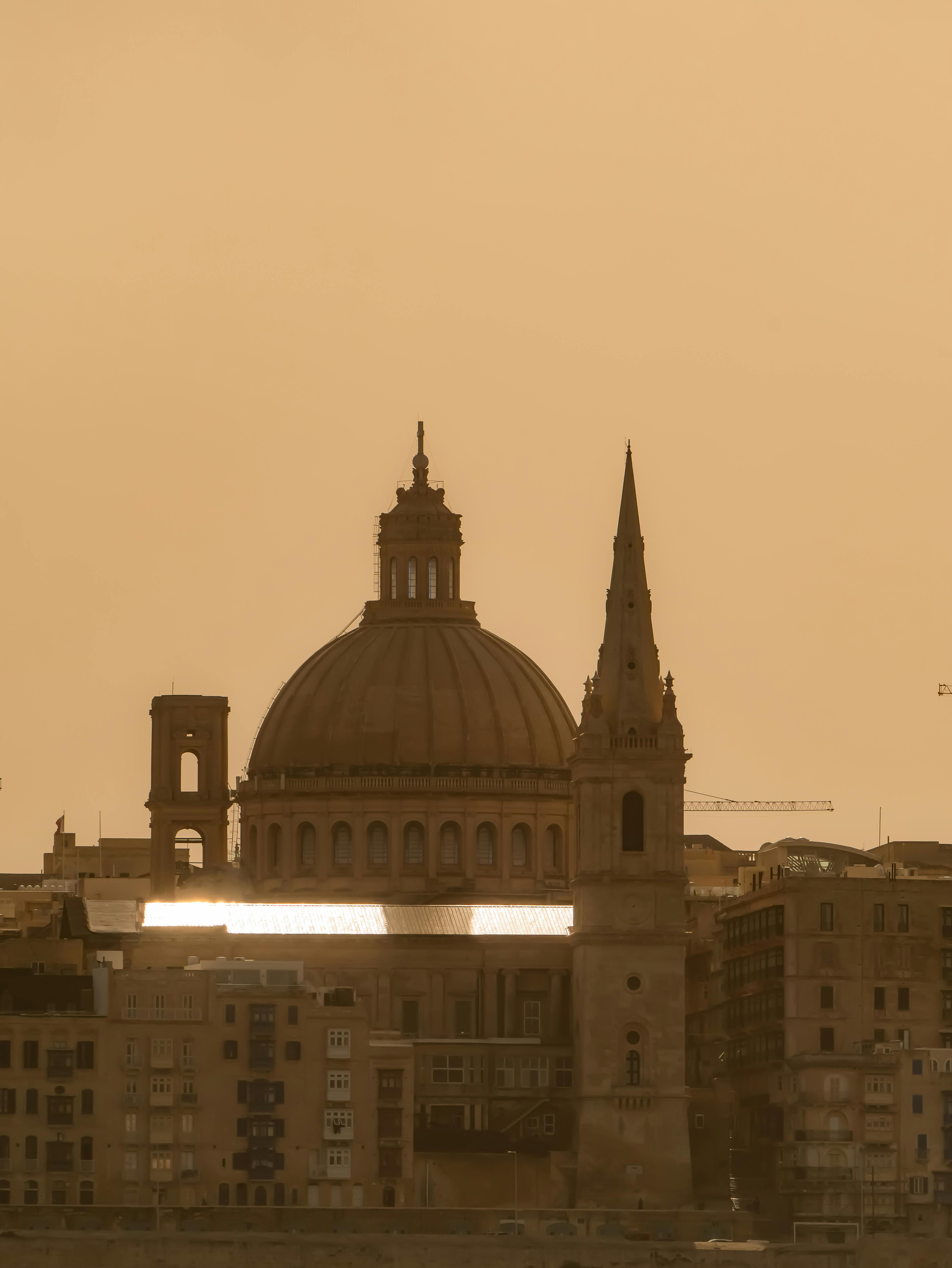 無料 暖かいセピア色の夕暮れ時のマルタのセントポール大聖堂と都市のスカイラインの美しい景色。 写真素材
