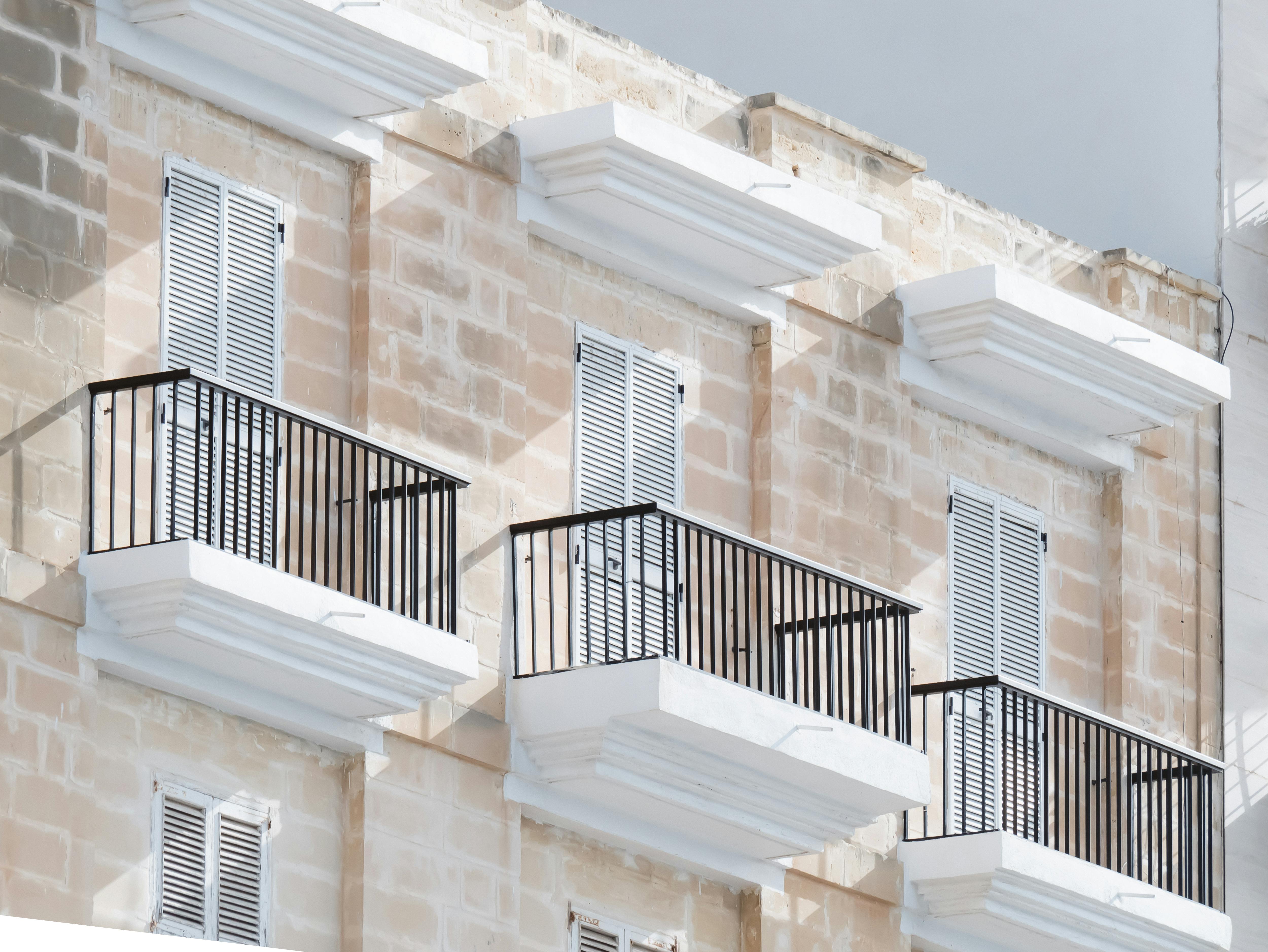 бесплатная Элегантные мальтийские балконы со ставнями на фасаде традиционного известнякового здания, залитые ярким дневным светом. Стоковое фото