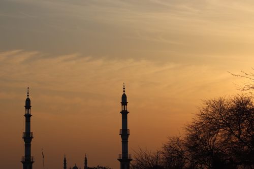 Free Silhouetted minarets against a vibrant sunset sky with bare trees. Stock Photo