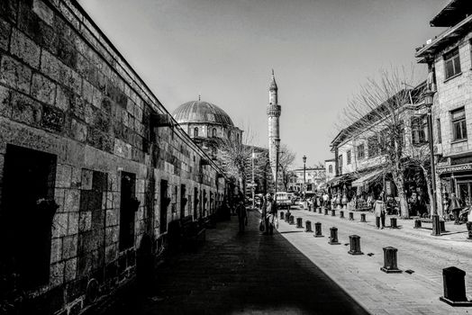 Black and white photo of a historic street and mosque, showcasing traditional architecture and daily life.