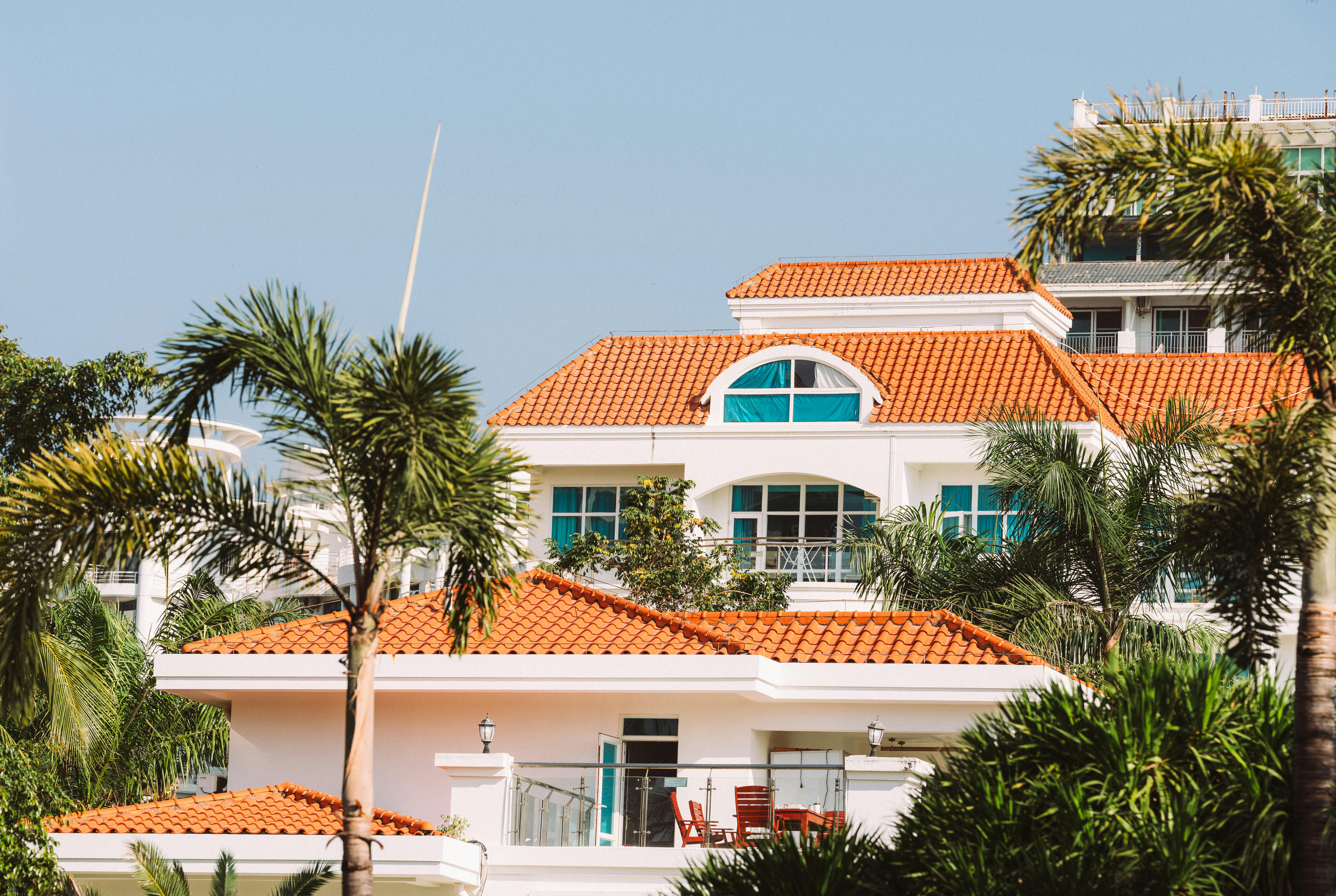 бесплатная Потрясающая вилла в средиземноморском стиле с оранжевой черепичной крышей и пышными пальмами. Стоковое фото