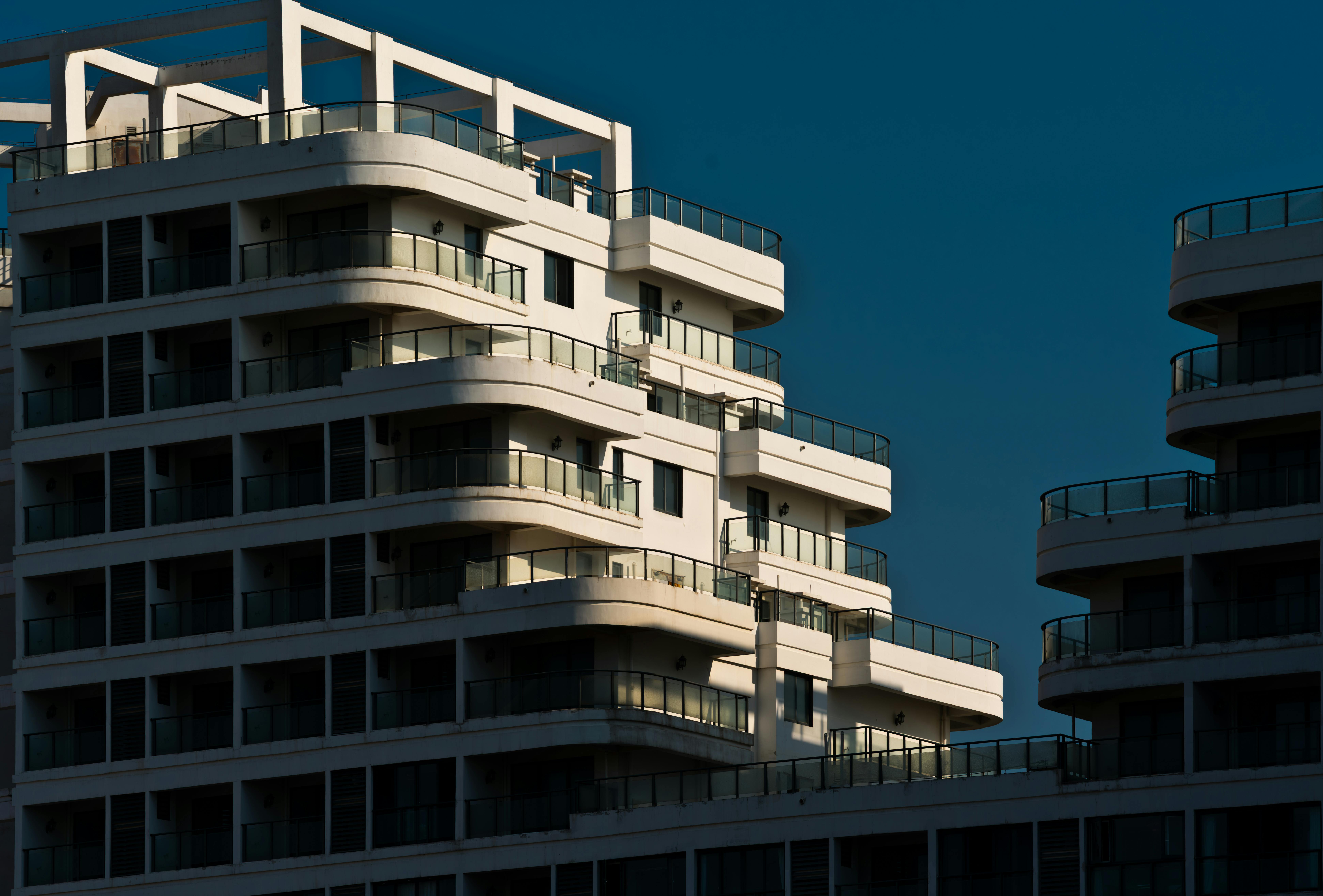 бесплатная Потрясающий вид на современный многоквартирный дом со стеклянными балконами на закате. Стоковое фото