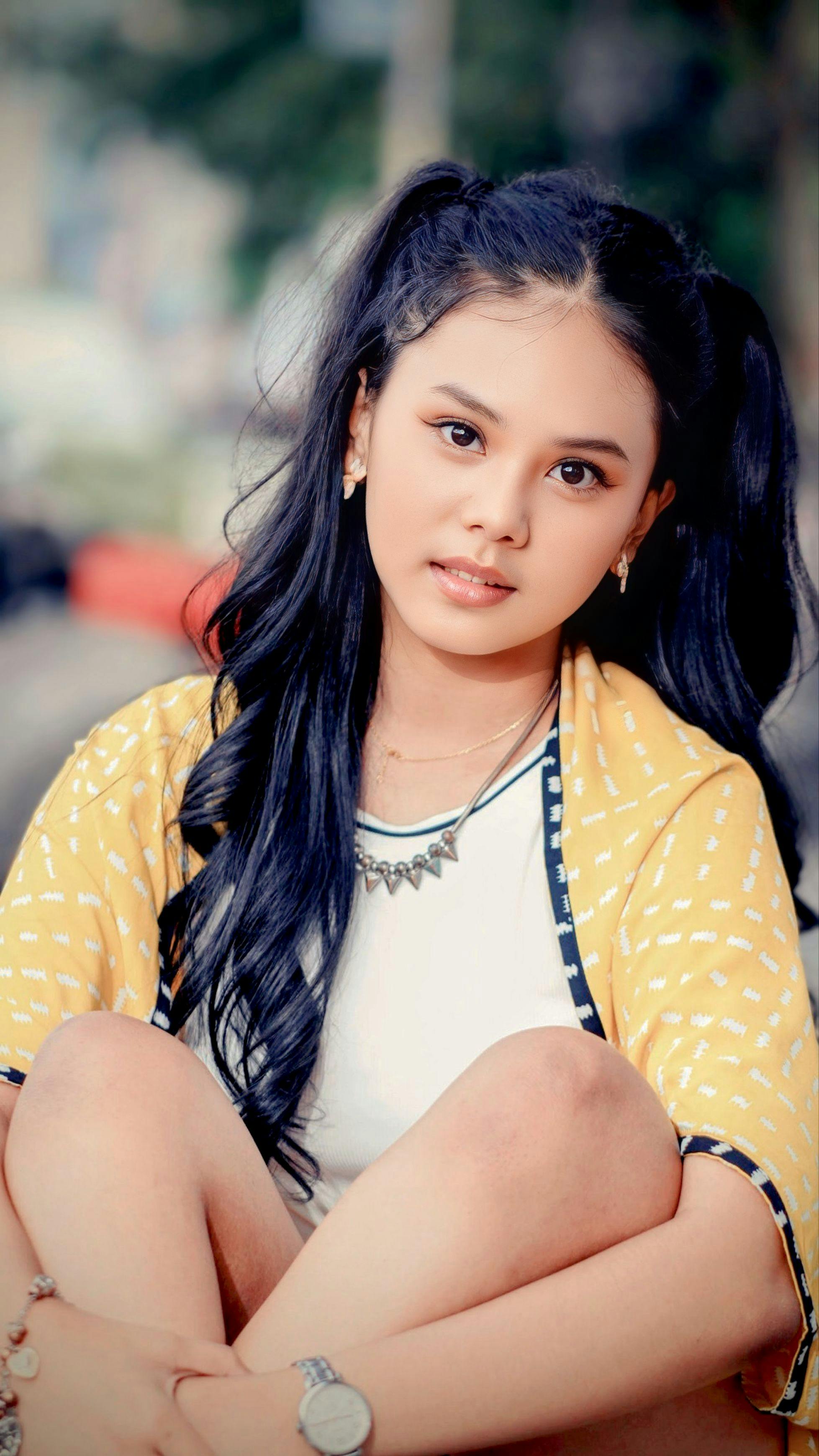 Beautiful young woman sitting outdoors in Bandung, Indonesia.