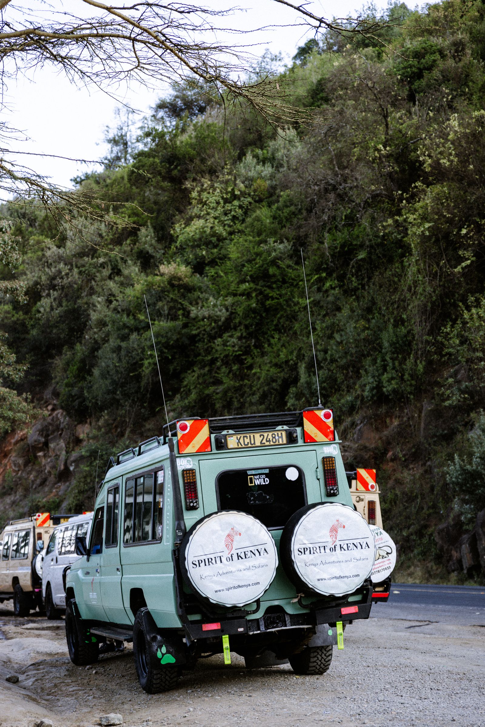 Safari vehicles on a road in Kenya, where soft bags pack easily into the four-wheel-drive