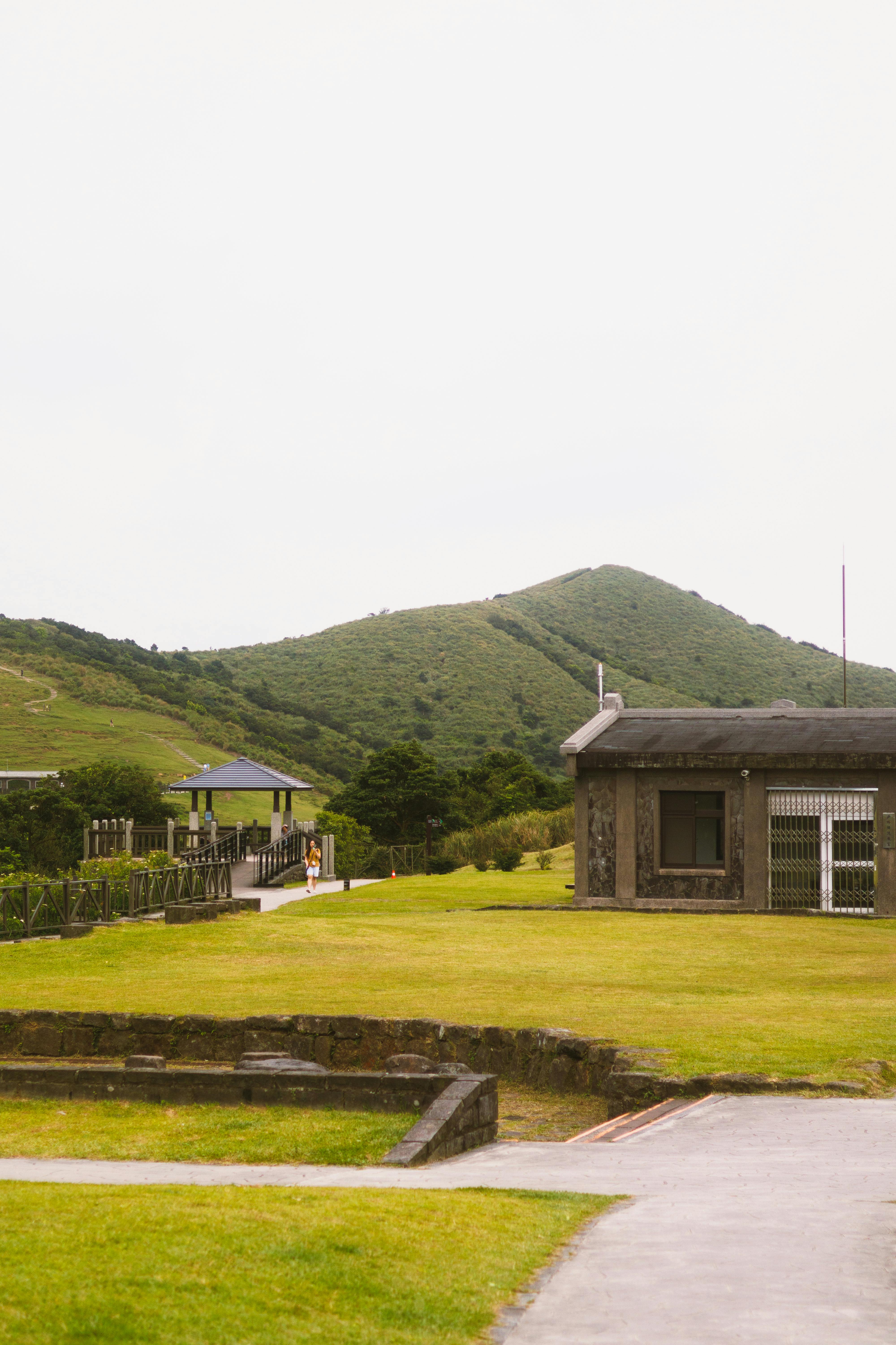 無料 緑豊かな丘と趣のある石造りの建物のある静かな田園風景。 写真素材