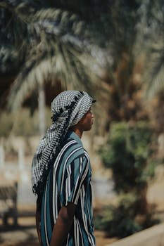 A man wearing a keffiyeh stands in a garden setting in Kano, Nigeria.