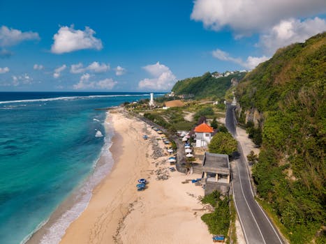 Aerial view of a Bali beach with a lighthouse and scenic coastline in Indonesia.