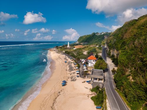 Free Aerial view of a Bali beach with a lighthouse and scenic coastline in Indonesia. Stock Photo