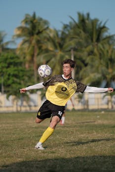 Action shot of a soccer player kicking the ball on a sunny day outdoors.