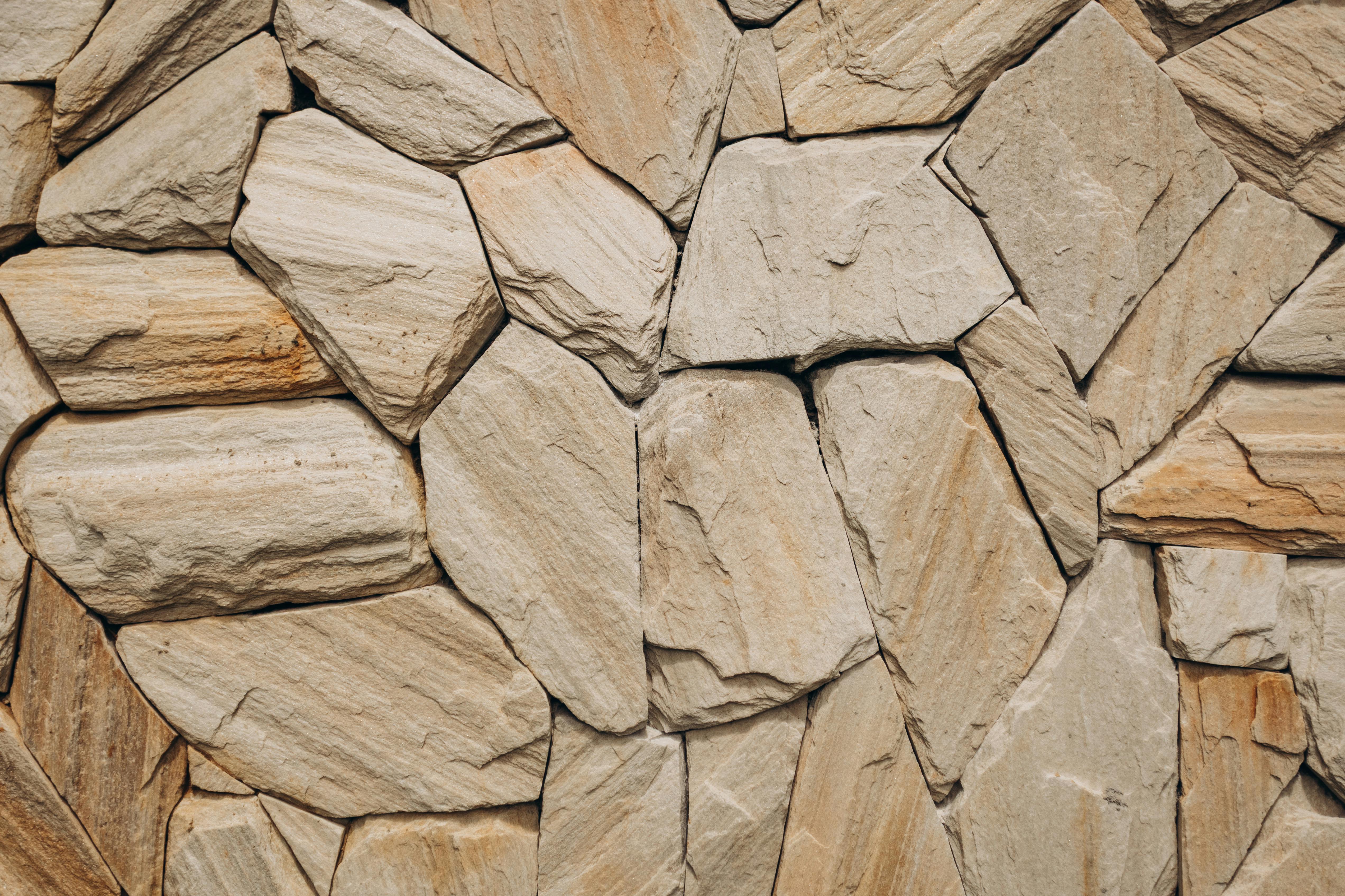 無料 ベージュトーンの凹凸のある岩を際立たせた詳細な天然石の壁テクスチャ。 写真素材