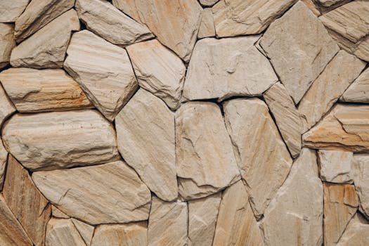 Detailed natural stone wall texture showcasing uneven rocks in beige tones.