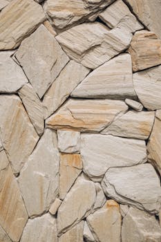 Detailed close-up of a beige stone wall texture with irregular shapes and earthy tones.