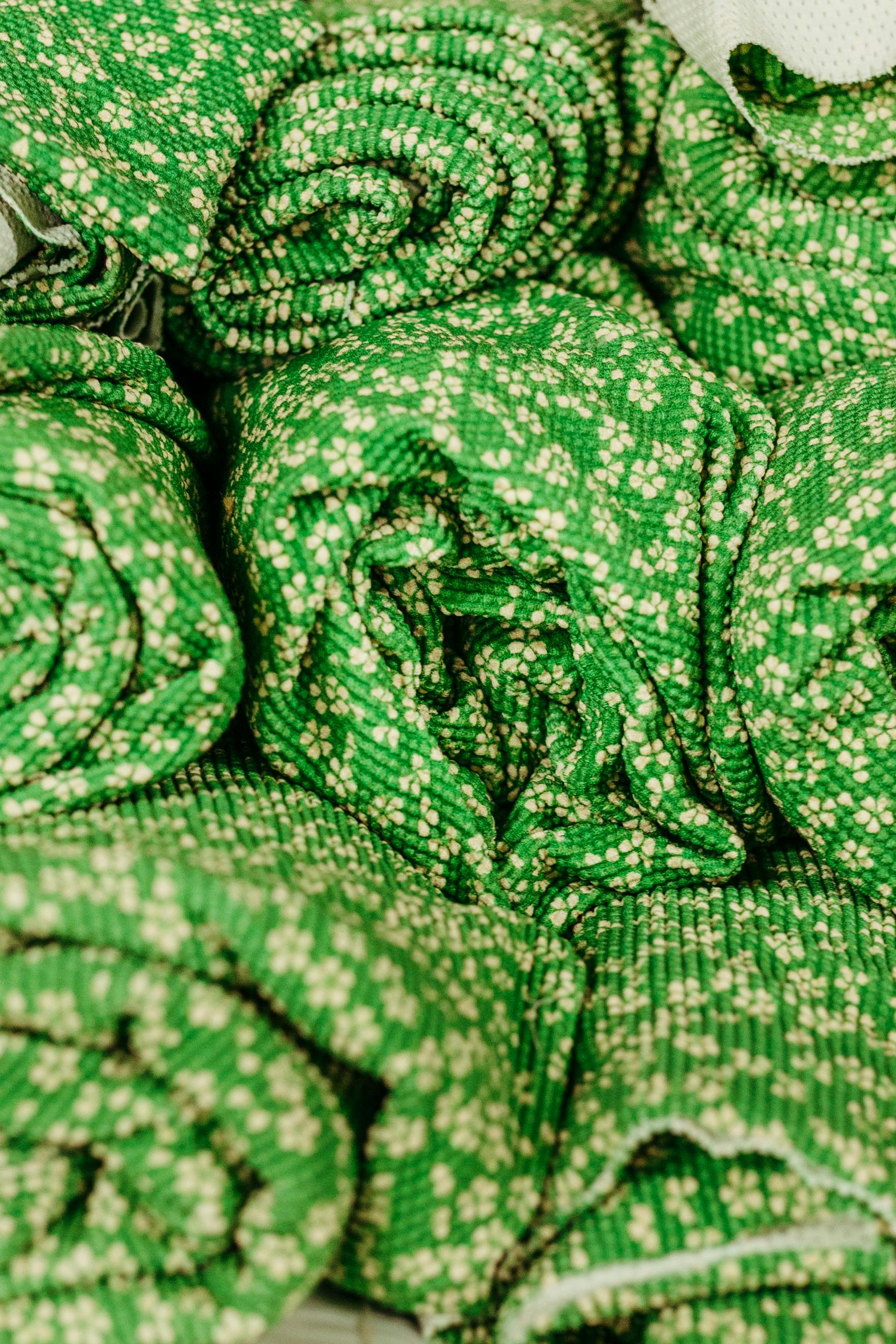 Free Close-up of rolled green fabrics with white floral patterns and textures. Stock Photo
