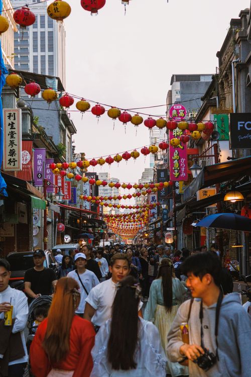 Free Crowded street in Asia decorated with red and yellow lanterns celebrating a vibrant festival. Stock Photo
