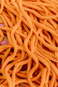 A close-up shot of intertwined vibrant orange textured cables, creating an abstract pattern.