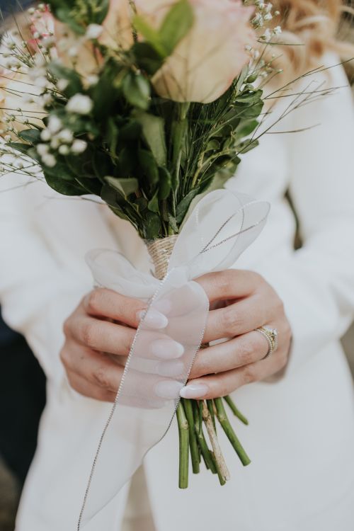 Free Close-up of a bride holding a beautiful bouquet with greenery and blossoms, highlighting wedding details. Stock Photo