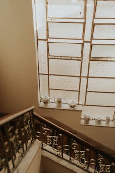 A beautifully aged staircase with ornate railings and a vintage tea set on a windowsill, creating a nostalgic ambiance.