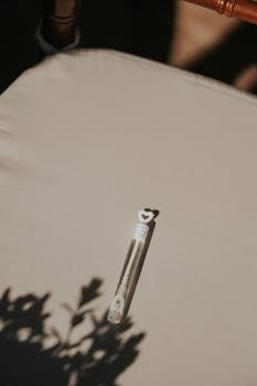 A bubble wand with a heart-shaped handle on a sunlit beige cushion casting shadows.