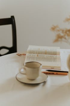 Warm and inviting setup with an open book, coffee cup, and mild decor on a table.