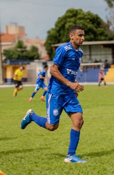 Soccer player in blue uniform running during a match on grass field.