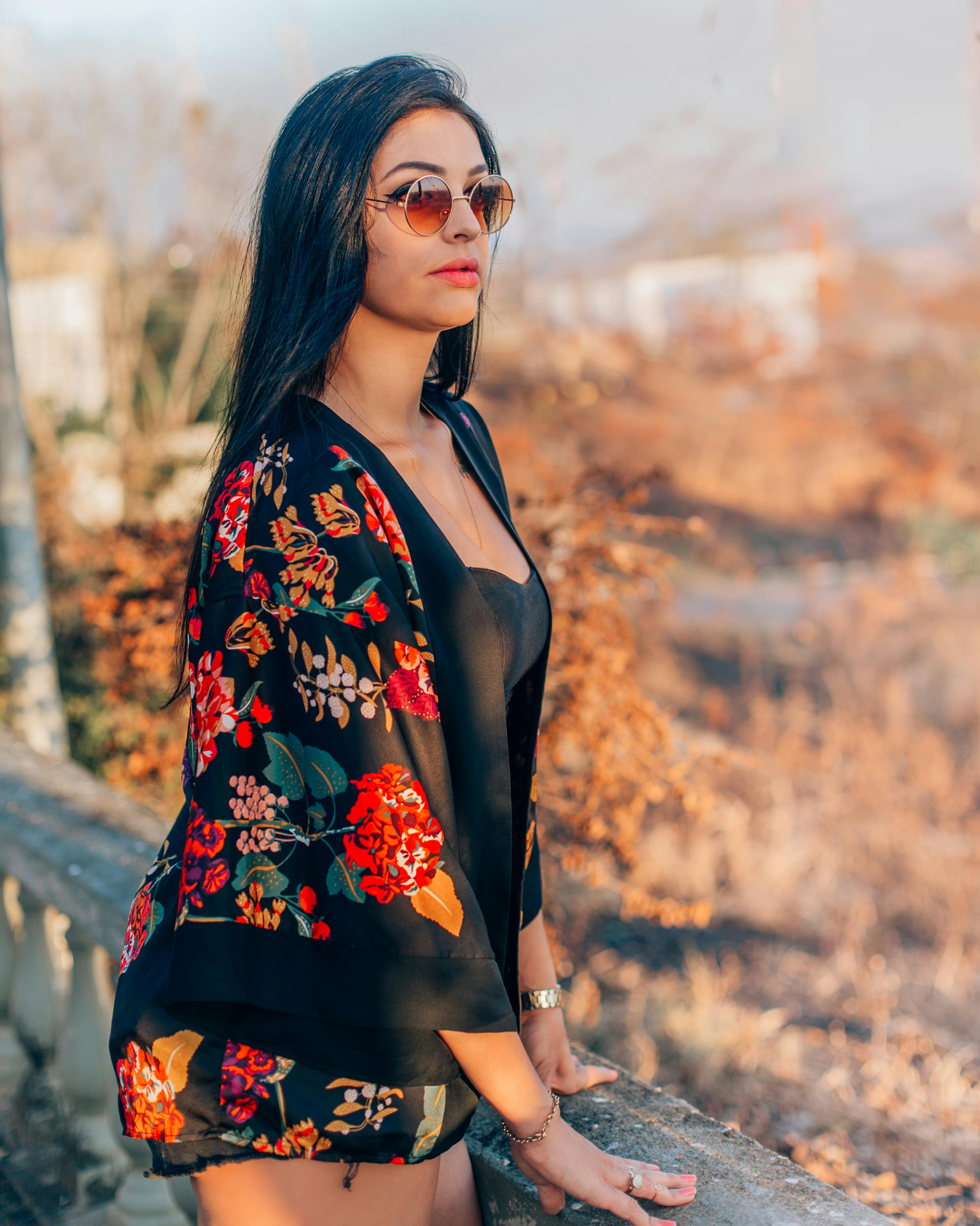 优雅的女人戴着太阳镜，穿着花卉图案的衣服，身处宁静的户外环境中