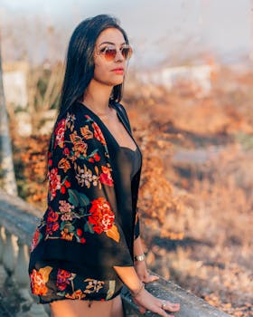 优雅的女人戴着太阳镜，穿着花卉图案的衣服，身处宁静的户外环境中