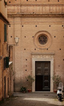 A rustic Italian street leading to an ornate historical building facade.