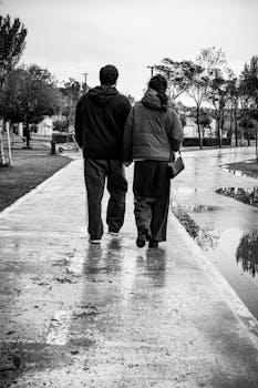 Couple walking hand in hand on a rainy day, creating a reflective mood.