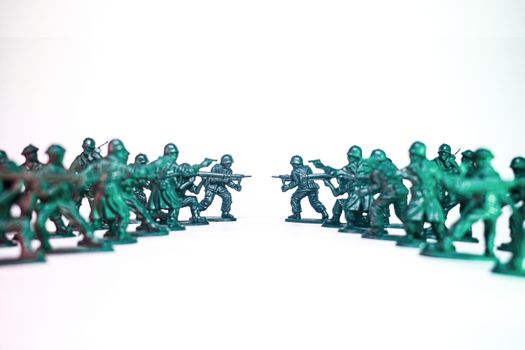 Green toy soldiers facing off on a white background, symbolic of conflict and strategy.